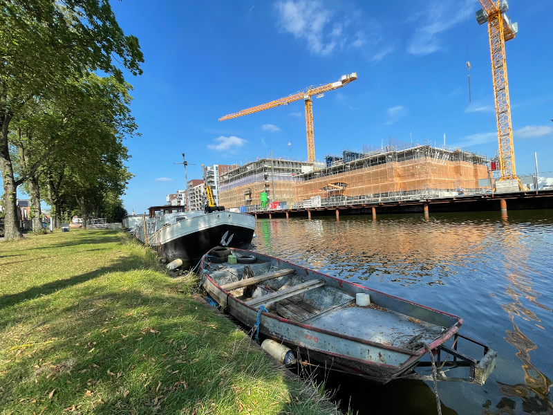 Bootjes in het Noordhollands Kanaal waar aan de overzijde woningen worden gebouwd.